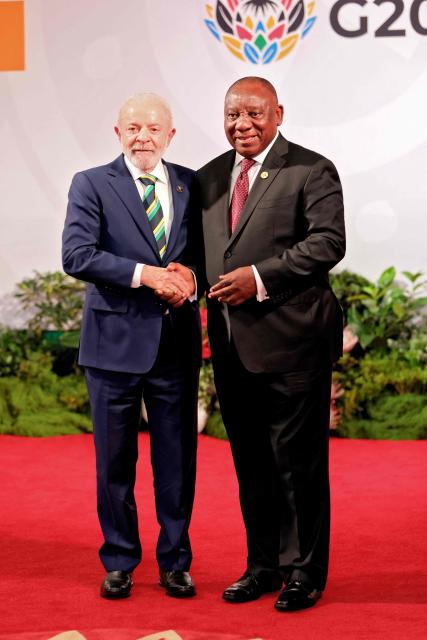 South Africa's President Cyril Ramaphosa (R) shakes hands with Brazil's President Luiz Inacio Lula da Silva (L) as he arrives for the opening of the G20 Leaders' Summit at the Nasrec Expo Centre in Johannesburg on November 22, 2025. (Photo by Halden KROG / POOL / AFP)