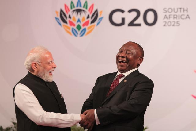 South African President Cyril Ramaphosa (R) welcomes Indian Prime Minister Narendra Modi as he arrives for the opening of the G20 Leaders' Summit at the Nasrec Expo Centre in Johannesburg on November 22, 2025. (Photo by Halden KROG / POOL / AFP)