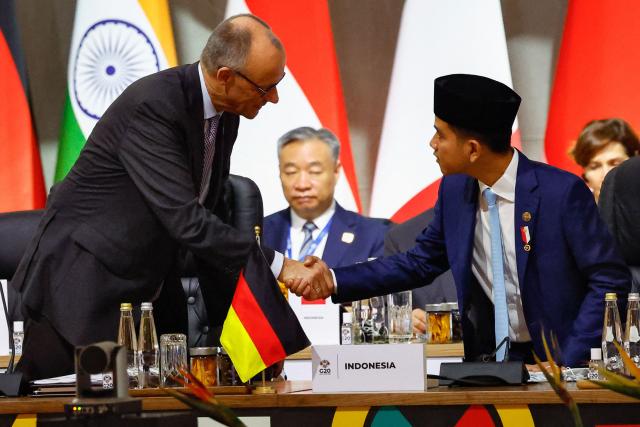 Indonesia's Vice President Gibran Rakabuming Raka shakes hands with German Chancellor Friedrich Merz during a G20 Leaders' Summit plenary session at the Nasrec Expo Centre in Johannesburg on November 22, 2025. (Photo by Thomas Mukoya / POOL / AFP)