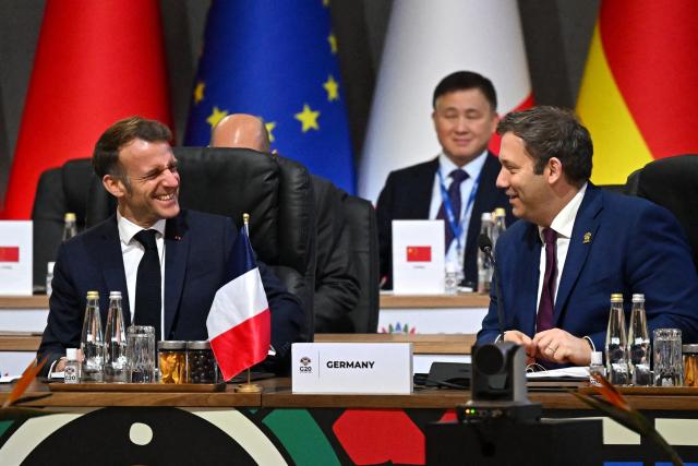 France's President Emmanuel Macron (L) share a laugh with German Finance Minister and Vice Chancellor Lars Klingbeil during a G20 Leaders' Summit plenary session at the Nasrec Expo Centre in Johannesburg on November 22, 2025. (Photo by Leon Neal / POOL / AFP)