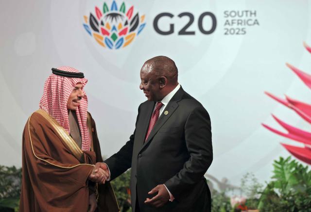 South African President Cyril Ramaphosa (R) welcomes Saudi Arabia's Foreign Minister Faisal bin Farhan Al Saud as he arrives for the opening of the G20 Leaders' Summit at the Nasrec Expo Centre in Johannesburg on November 22, 2025. (Photo by Halden KROG / POOL / AFP)