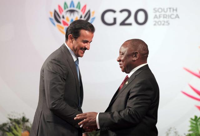 South African President Cyril Ramaphosa (R) welcomes Qatar's Emir Sheikh Tamim bin Hamad Al Thani as he arrives for the opening of the G20 Leaders' Summit at the Nasrec Expo Centre in Johannesburg on November 22, 2025. (Photo by Halden KROG / POOL / AFP)