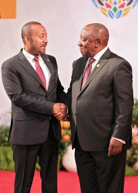 South African President Cyril Ramaphosa (R) welcomes Ethiopian Prime Minister Abiy Ahmed Ali as he arrives for the opening of the G20 Leaders' Summit at the Nasrec Expo Centre in Johannesburg on November 22, 2025. (Photo by Halden KROG / POOL / AFP)