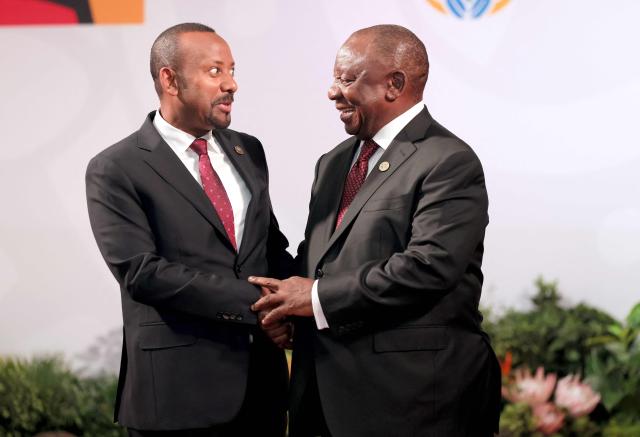 South African President Cyril Ramaphosa (R) welcomes Ethiopian Prime Minister Abiy Ahmed Ali as he arrives for the opening of the G20 Leaders' Summit at the Nasrec Expo Centre in Johannesburg on November 22, 2025. (Photo by Halden KROG / POOL / AFP)
