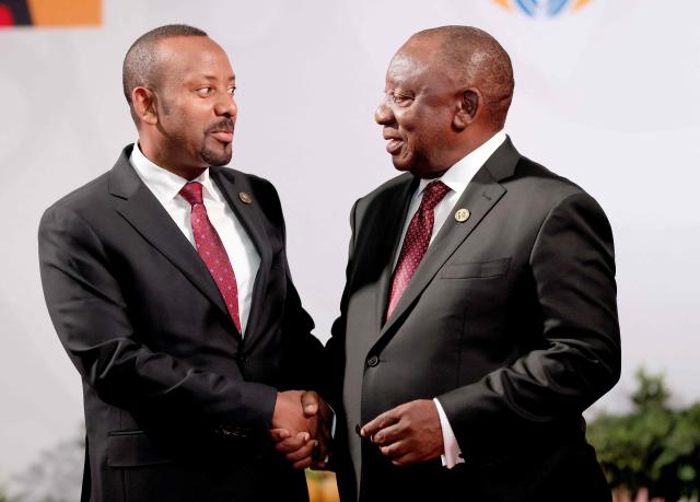 South African President Cyril Ramaphosa (R) welcomes Ethiopian Prime Minister Abiy Ahmed Ali as he arrives for the opening of the G20 Leaders' Summit at the Nasrec Expo Centre in Johannesburg on November 22, 2025. (Photo by Halden KROG / POOL / AFP)