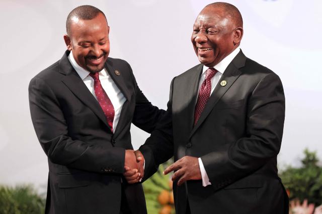 South African President Cyril Ramaphosa (R) welcomes Ethiopian Prime Minister Abiy Ahmed Ali as he arrives for the opening of the G20 Leaders' Summit at the Nasrec Expo Centre in Johannesburg on November 22, 2025. (Photo by Halden KROG / POOL / AFP)