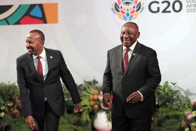 South African President Cyril Ramaphosa (R) welcomes Ethiopian Prime Minister Abiy Ahmed Ali as he arrives for the opening of the G20 Leaders' Summit at the Nasrec Expo Centre in Johannesburg on November 22, 2025. (Photo by Halden KROG / POOL / AFP)