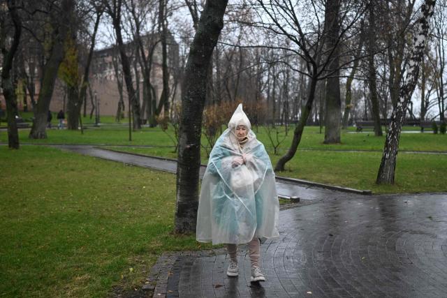 An elderly woman wearing a raincoat walks in a park in Kyiv on November 22, 2025, amid the Russian invasion of Ukraine. (Photo by Sergei GAPON / AFP)