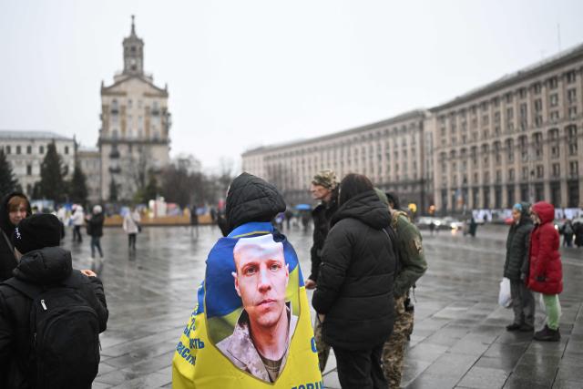 A demonstrator wrapped in a Ukrainian flag with a photo of a Ukrainian serviceman attends a rally in support of missing and captured soldiers, in Kyiv on November 22, 2025, amid the Russian invasion of Ukraine. (Photo by Sergei GAPON / AFP)
