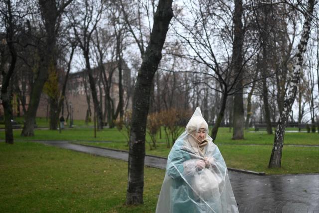 An elderly woman wearing a raincoat walks in a park in Kyiv on November 22, 2025, amid the Russian invasion of Ukraine. (Photo by Sergei GAPON / AFP)