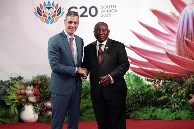 South African President Cyril Ramaphosa (R) welcomes Spain's Prime Minister Pedro Sanchez as he arrives for the opening of the G20 Leaders' Summit at the Nasrec Expo Centre in Johannesburg on November 22, 2025. (Photo by POOL / AFP)