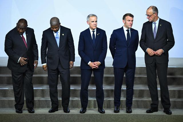 South African President Cyril Ramaphosa (L) Canadian Prime Minister Mark Carney (C) France's President Emmanuel Macron (2nd R) and German Chancellor Friedrich Merz (R) stand together as they attend a family photo event during a G20 Leaders' Summit plenary session at the Nasrec Expo Centre in Johannesburg on November 22, 2025. (Photo by Leon Neal / POOL / AFP)