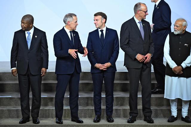 Angola's President Joao Lourenco (L) Canadian Prime Minister Mark Carney (2ndL) France's President Emmanuel Macron (C), German Chancellor Friedrich Merz (2ndR) and India's Prime Minister Narendra Modi stand together as they attend a family photo event during a G20 Leaders' Summit plenary session at the Nasrec Expo Centre in Johannesburg on November 22, 2025. (Photo by Leon Neal / POOL / AFP)