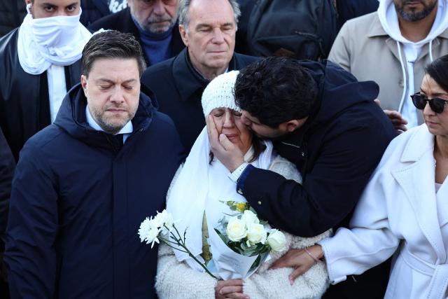 TOPSHOT - French anti-drug activist Amine Kessaci (C-R) kisses his mother Ouassila Benhamdi Kessaci (C) as Marseille's mayor Benoit Payan (L) and people gather to take part in a march in tribute to Mehdi Kessaci at the roundabout where he was murdered  and to protest against drug trafficking, in Marseille, southern France on November 22, 2025. Mehdi Kessaci, the 22-year-old younger brother of Amine Kessaci, who wanted to become a police officer, was shot dead near a concert hall by two people on a motorbike, on November 13. More than a week after this tragedy, Mehdi Kessaci's family is calling for a gathering at the roundabout where he was murdered by two men on a motorbike under the slogan: "Justice for Mehdi, 20, who died for nothing". Other initiatives are planned in some 25 towns and cities. (Photo by CLEMENT MAHOUDEAU / AFP)