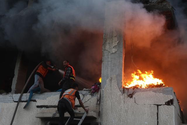 Civil defence personnel search a burning house targeted by Israeli airstrikes in Gaza City, on November 22, 2025. Gaza's civil defence agency said 21 people were killed and dozens more wounded in multiple Israeli air strikes on the Palestinian territory on November 22. (Photo by Omar AL-QATTAA / AFP)