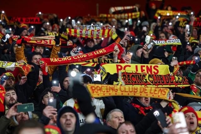 Lens' supporters hold up their scarves during the French L1 football match between RC Lens and RC Strasbourg Alsace at the Stade Bollaert-Delelis in Lens, northern France, on November 22, 2025. (Photo by Sameer Al-DOUMY / AFP)