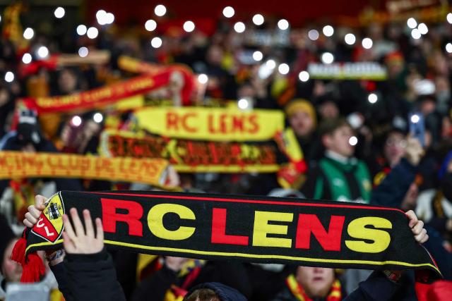 Lens' supporters hold up their scarves during the French L1 football match between RC Lens and RC Strasbourg Alsace at the Stade Bollaert-Delelis in Lens, northern France, on November 22, 2025. (Photo by Sameer Al-DOUMY / AFP)