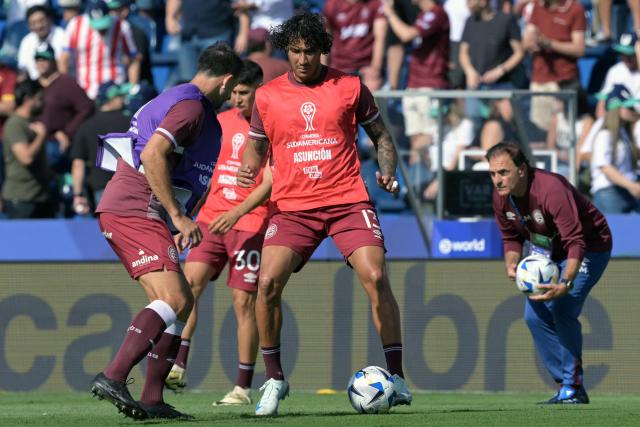 Lanus' defender #13 Jose Maria Canale and Lanus' defender #24 Carlos Izquierdoz warm up before the start of the Copa Sudamericana final football match between Argentina's Lanus and Brazil's Atletico Mineiro at the Defensores del Chaco stadium in Asuncion on November 22, 2025. (Photo by JUAN MABROMATA / AFP)