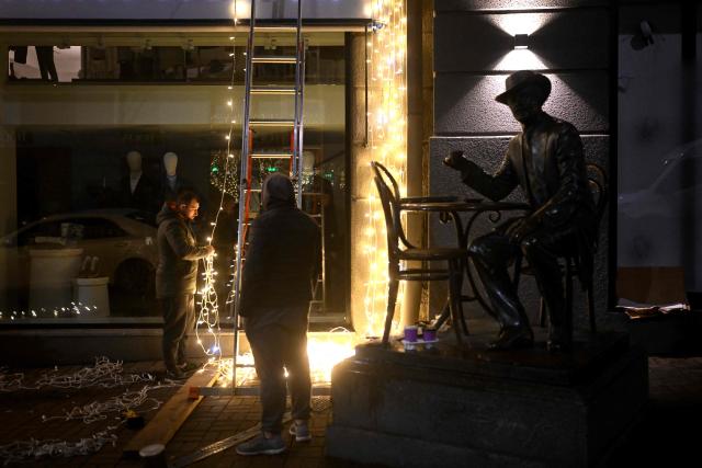 Workers decorate the facade of a clothing shop with Christmas illuminations in Kyiv on November 22, 2025, amid the Russian invasion of Ukraine. (Photo by Sergei GAPON / AFP)
