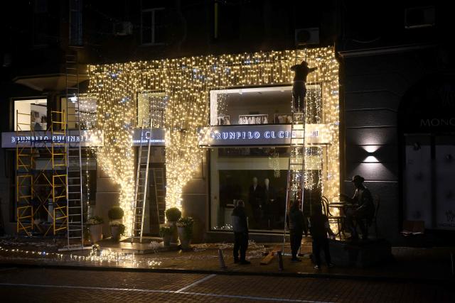 Workers decorate the facade of a clothing shop with Christmas illuminations in Kyiv on November 22, 2025, amid the Russian invasion of Ukraine. (Photo by Sergei GAPON / AFP)