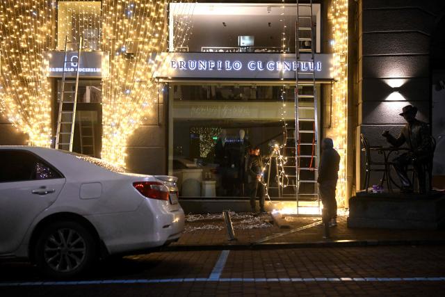 Workers decorate the facade of a clothing shop with Christmas illuminations in Kyiv on November 22, 2025, amid the Russian invasion of Ukraine. (Photo by Sergei GAPON / AFP)