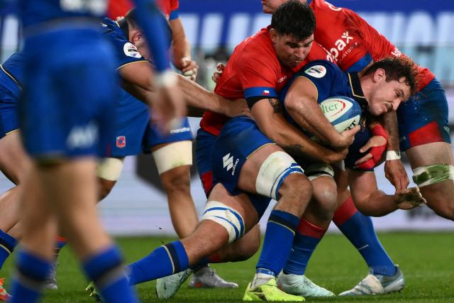 Italy's flanker Michele Lamaro (C) is tackled by Chile's flanker Clemente Saavedra (L) during the Autumn Nations Series international rugby union test match between Italy and Chile at Stadio Luigi Ferraris stadium in Genoa, on November 22, 2025. (Photo by MARCO BERTORELLO / AFP)