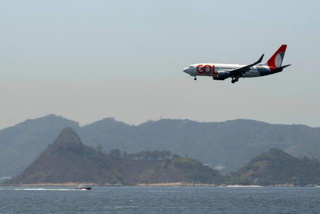 (FILES) A plane of Brazilian airline Gol flies over Guanabara Bay before landing at Santos Dumont airport in Rio de Janeiro, Brazil, on October 16, 2024. Six airlines -Brazil's GOL, Colombia's Avianca, Chile's Latam, Spain's Iberia, Portugal's TAP, and Trinidad's Caribbean- cancelled their flights to Venezuela on November 22, 2025 after the United States warned civil aviation authorities of an ‘increase in military activity’ amid the deployment of US forces in the Caribbean, the airline association told AFP. (Photo by Pablo PORCIUNCULA / AFP)