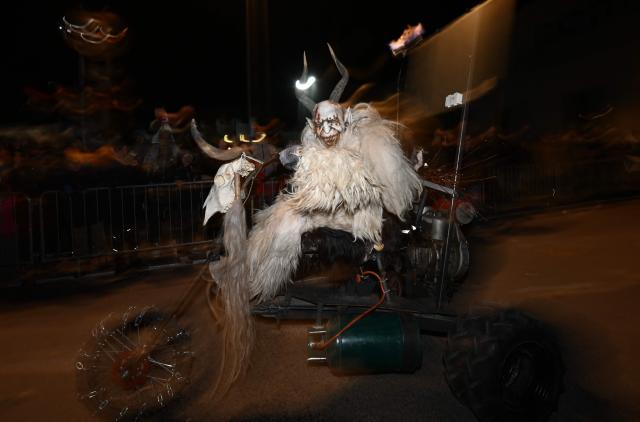 A reveller dressed as traditional folkloric figure "Krampus", rides a motorcycle as they take part in the traditional parade during the "Night of Hell" in Lana, northern Italy, on November 22, 2025. An old tradition that takes place in the Alps of Tirol northern Italy, the traditional Krampus creature (half-goat, half-demon figure) punishes people who misbehaved during Christmas season. (Photo by Stefano RELLANDINI / AFP)