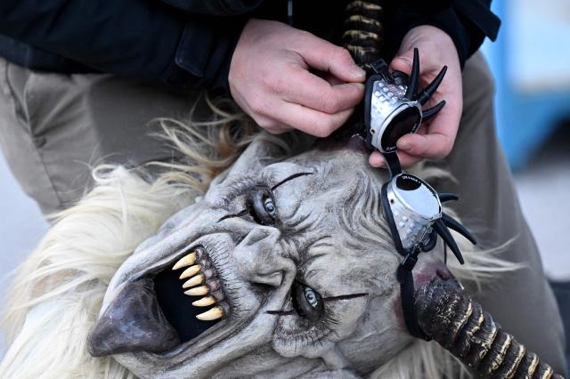 A participant holds their traditional folkloric figure "Krampus", ahead of the traditional parade during the "Night of Hell" in Lana, northern Italy, on November 22, 2025. An old tradition that takes place in the Alps of Tirol northern Italy, the traditional Krampus creature (half-goat, half-demon figure) punishes people who misbehaved during Christmas season. (Photo by Stefano RELLANDINI / AFP)