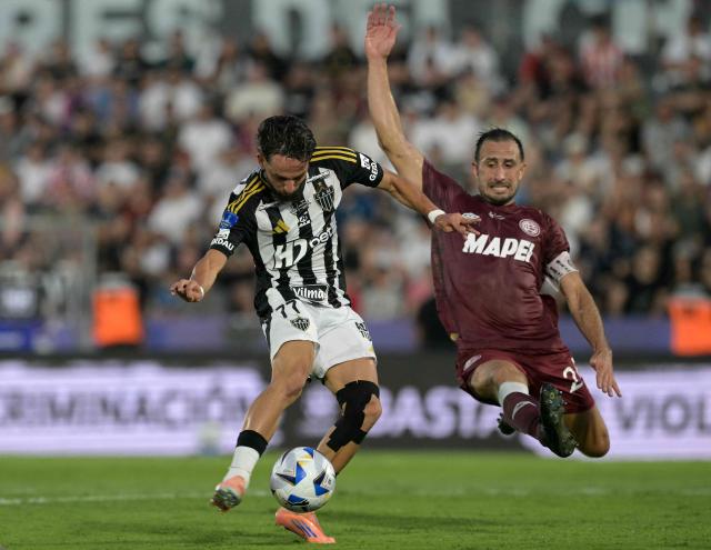 Atletico Mineiro's forward #77 Biel Teixeira (L) kicks the ball past Lanus' defender #24 Carlos Izquierdoz (R) during the Copa Sudamericana final football match between Argentina's Lanus and Brazil's Atletico Mineiro at the Defensores del Chaco stadium in Asuncion on November 22, 2025. (Photo by Juan MABROMATA / AFP)