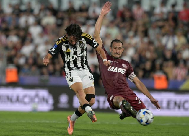 Atletico Mineiro's forward #77 Biel Teixeira (L) kicks the ball past Lanus' defender #24 Carlos Izquierdoz (R) during the Copa Sudamericana final football match between Argentina's Lanus and Brazil's Atletico Mineiro at the Defensores del Chaco stadium in Asuncion on November 22, 2025. (Photo by Juan MABROMATA / AFP)