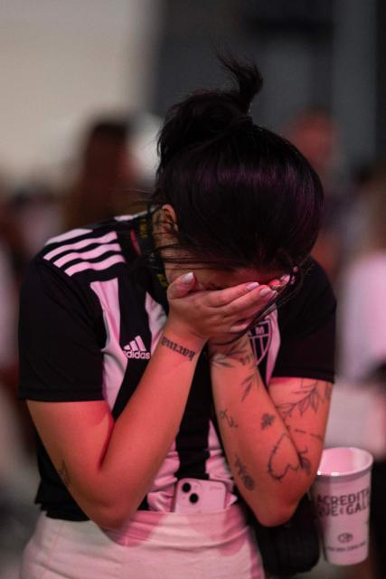 A fan of Atletico Mineiro reacts as she watches on TV the end of the Copa Sudamericana final football match between Argentina’s Lanus and Brazil’s Atletico Mineiro at the Arena MRV stadium in Belo Horizonte, Brazil on November 22, 2025. (Photo by DOUGLAS MAGNO / AFP)