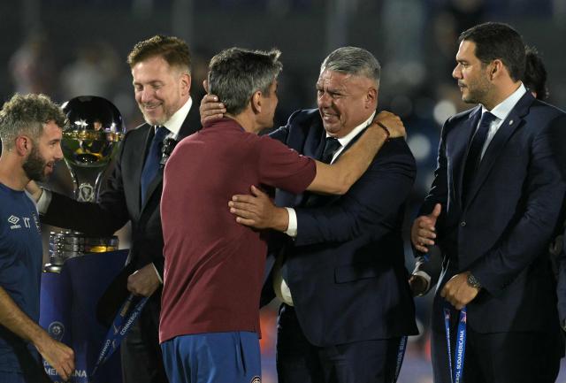 Lanus' head coach Mauricio Pellegrino (C-L) and Argentine Football Association (AFA) president Claudio Tapia (C-R) hug during the award ceremony of the Copa Sudamericana final football match between Argentina's Lanus and Brazil's Atletico Mineiro at the Defensores del Chaco stadium in Asuncion on November 22, 2025. (Photo by JUAN MABROMATA / AFP)