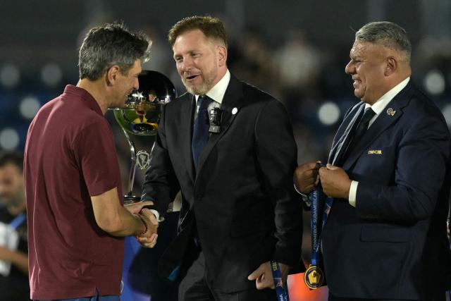 Lanus' head coach Mauricio Pellegrino (L) and Conmebol's president Paraguayan Alejandro Dominguez (C) shake hands past Argentine Football Association (AFA) president Claudio Tapia (R) during the award ceremony of the Copa Sudamericana final football match between Argentina's Lanus and Brazil's Atletico Mineiro at the Defensores del Chaco stadium in Asuncion on November 22, 2025. (Photo by JUAN MABROMATA / AFP)