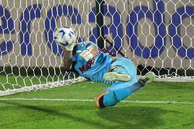 Lanus' goalkeeper #26 Nahuel Losada makes a save past Atletico Mineiro's defender #14 Vitor Hugo (out of frame) to win the penalty shootout of the Copa Sudamericana final football match between Argentina's Lanus and Brazil's Atletico Mineiro at the Defensores del Chaco stadium in Asuncion on November 22, 2025. (Photo by JOSE BOGADO / AFP)