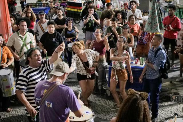 People celebrate in the streets following the arrest of former President Jair Bolsonaro (2019–2023) in Rio de Janeiro, Brazil on November 22, 2025. Ex-President Jair Bolsonaro -who in September had been sentenced to 27 years in prison over a botched coup bid but has yet to begin serving his term- was taken from house arrest into police custody as he is considered a flight risk according to a Supreme Court ruling. (Photo by BRUNO KAIUCA / AFP)