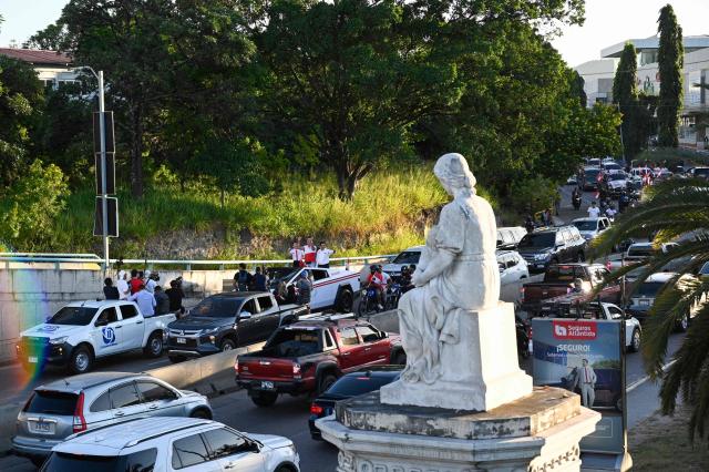 Honduran presidential candidate and media personality Salvador Nasralla (C), of the right-wing Liberal Party (PL), waves alongside his wife and congressional candidate Iroshka Elvir, and Tegucigalpa’s mayoral candidate Eliseo Castro (R), during his campaign closing rally in Tegucigalpa on November 22, 2025. Hondurans will head to the polls on November 30 to elect a president, 128 members of the National Congress, 298 mayors, and 20 representatives to the Central American Parliament. (Photo by Orlando SIERRA / AFP)