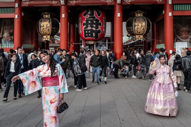 Asian tourists pose during a visit to Sensoji Temple in the Asakusa district of central Tokyo on November 23, 2025. (Photo by Philip FONG / AFP)