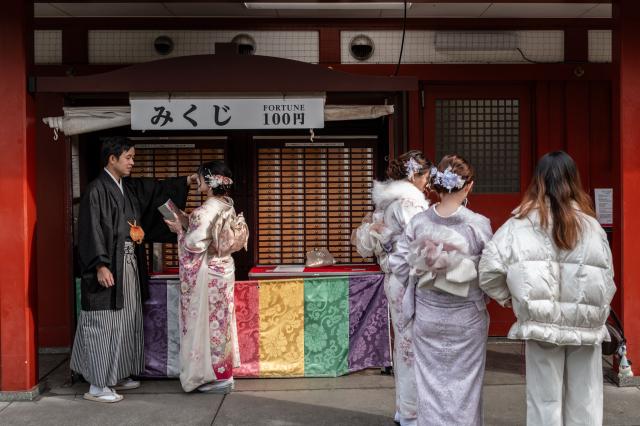 Asian tourists pose during a visit to Sensoji Temple in the Asakusa district of central Tokyo on November 23, 2025. (Photo by Philip FONG / AFP)