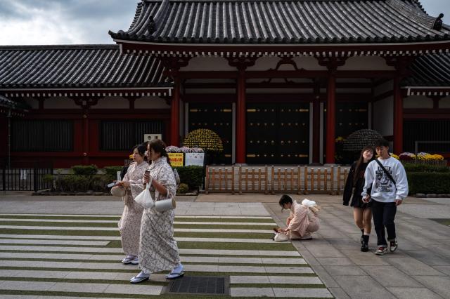 Asian tourists pose during a visit to Sensoji Temple in the Asakusa district of central Tokyo on November 23, 2025. (Photo by Philip FONG / AFP)