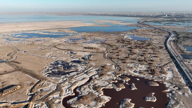 An aerial view shows salt mounds emerging from Lake Najaf or Bahr Al-Najaf (Najaf Sea), an inland lake in southern Iraq, some 10 kilometers southwest of the Iraqi city of Najaf on November 22, 2025. Known as the Najaf Sea, the inland lake has lost more than 10,000 acres of its surface water according to local enviromentalists. The waters, once one of the most important water resources in central Iraq, is deteriorating reflecting a broader pattern of water scarcity driven by upstream damming, climate change, and reduced rainfall. (Photo by Qassem al-KAABI / AFP)