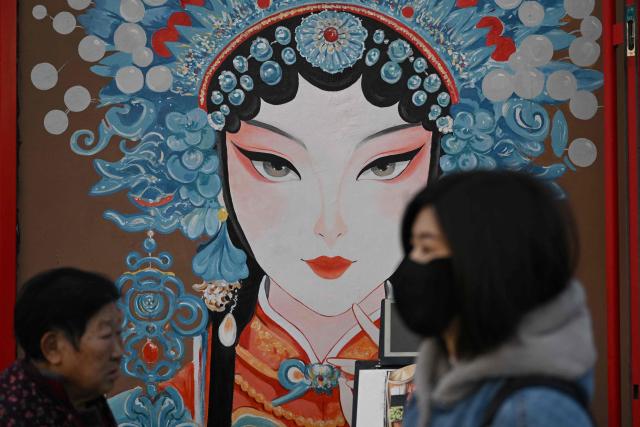 People walk past a mural outside a restaurant in Beijing on November 23, 2025. (Photo by Pedro PARDO / AFP)