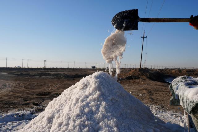 Salt is shovelled into a pile from Lake Najaf or Bahr Al-Najaf (Najaf Sea), an inland lake in southern Iraq, some 10 kilometers southwest of the Iraqi city of Najaf on November 22, 2025. Known as the Najaf Sea, the inland lake has lost more than 10,000 acres of its surface water according to local environmentalists. The waters, once one of the most important water resources in central Iraq, is deteriorating reflecting a broader pattern of water scarcity driven by upstream damming, climate change, and reduced rainfall. (Photo by Qassem al-KAABI / AFP)