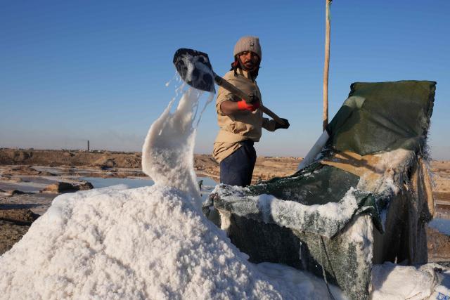 A man shovels salt from Lake Najaf or Bahr Al-Najaf (Najaf Sea), an inland lake in southern Iraq, some 10 kilometers southwest of the Iraqi city of Najaf on November 22, 2025. Known as the Najaf Sea, the inland lake has lost more than 10,000 acres of its surface water according to local environmentalists. The waters, once one of the most important water resources in central Iraq, is deteriorating reflecting a broader pattern of water scarcity driven by upstream damming, climate change, and reduced rainfall. (Photo by Qassem al-KAABI / AFP)