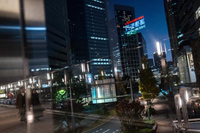 People walk at the business area near Tokyo's Shimbashi district at dusk on November 23, 2025. (Photo by Philip FONG / AFP)