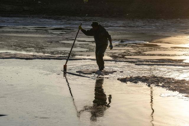 A man collects salt from Lake Najaf or Bahr Al-Najaf (Najaf Sea), an inland lake in southern Iraq, some 10 kilometers southwest of the Iraqi city of Najaf on November 22, 2025. Known as the Najaf Sea, the inland lake has lost more than 10,000 acres of its surface water according to local environmentalists. The waters, once one of the most important water resources in central Iraq, is deteriorating reflecting a broader pattern of water scarcity driven by upstream damming, climate change, and reduced rainfall. (Photo by Qassem al-KAABI / AFP)