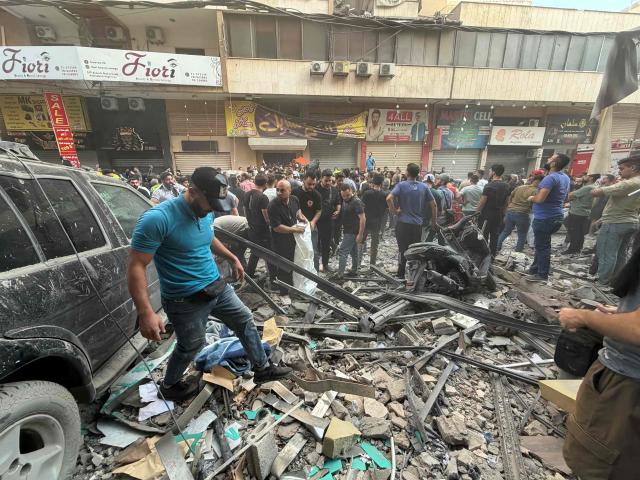 People gather looking at the debris following a targeted Israeli military strike on a residential building in the Haret Hreik neighbourhood of Beirut's southern suburbs on November 23, 2025. Israel's military said on November 23, 2025, that it had carried out a strike on a senior member of the Iran-backed Hezbollah militant group in Lebanon's capital. (Photo by Ibrahim AMRO / AFP)