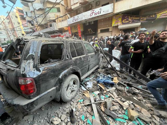 People gather as they look at the debris following an Israeli military strike targeting a residential building in the Haret Hreik neighbourhood, of Beirut's southern suburbs on November 23, 2025. Israel's military said on November 23, 2025, that it had carried out a strike on a senior member of the Iran-backed Hezbollah militant group in Lebanon's capital. (Photo by Ibrahim AMRO / AFP)
