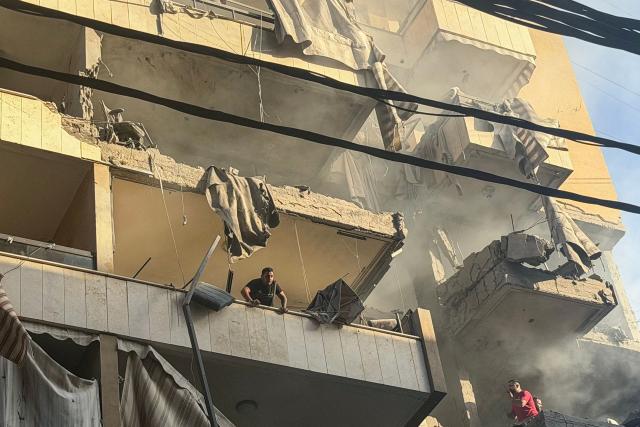 A man looks out from a balcony following an Israeli military strike targeting a residential building in the Haret Hreik neighbourhood, of Beirut's southern suburbs on November 23, 2025. Israel's military said on November 23, 2025, that it had carried out a strike on a senior member of the Iran-backed Hezbollah militant group in Lebanon's capital. (Photo by Ibrahim AMRO / AFP)