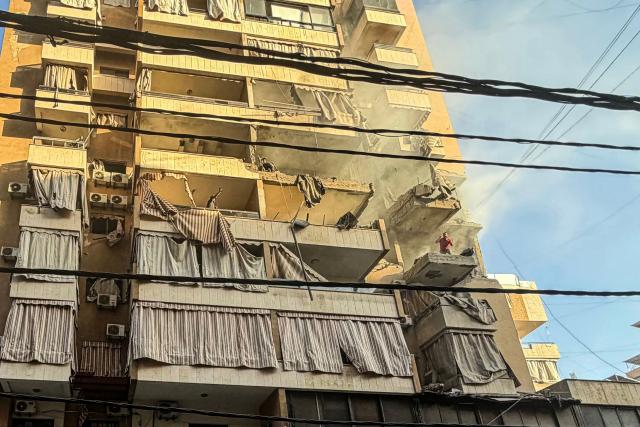 TOPSHOT - A man shouts as he stands on the balcony of a residential building targeted by an Israeli military strike in the Haret Hreik neighbourhood, of Beirut's southern suburbs on November 23, 2025. Israel's military said on November 23, 2025, that it had carried out a strike on a senior member of the Iran-backed Hezbollah militant group in Lebanon's capital. (Photo by Ibrahim AMRO / AFP)